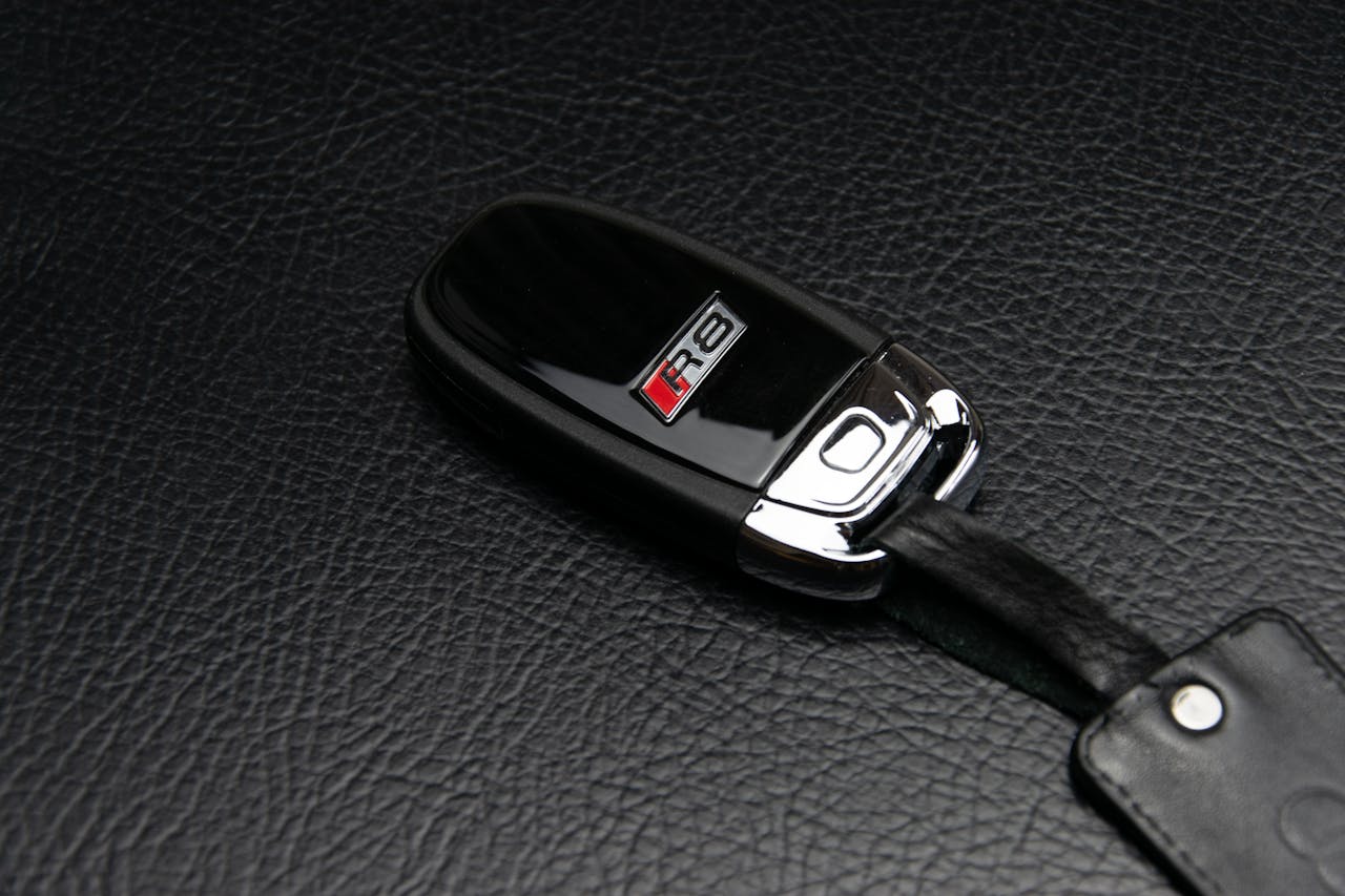 Close-up of a luxury car key fob resting on a textured leather surface, symbolizing elegance.