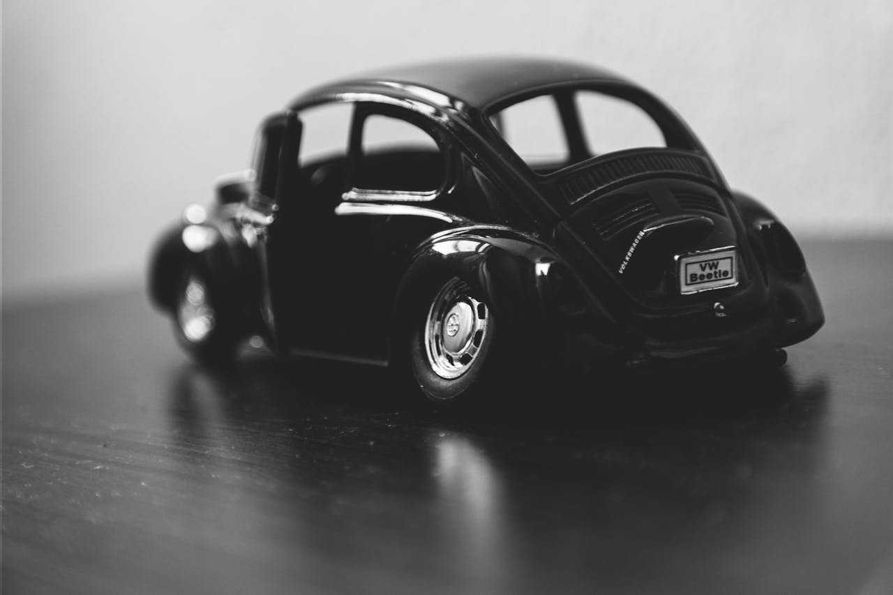 Black and white macro of a classic VW Beetle toy car model on a table.